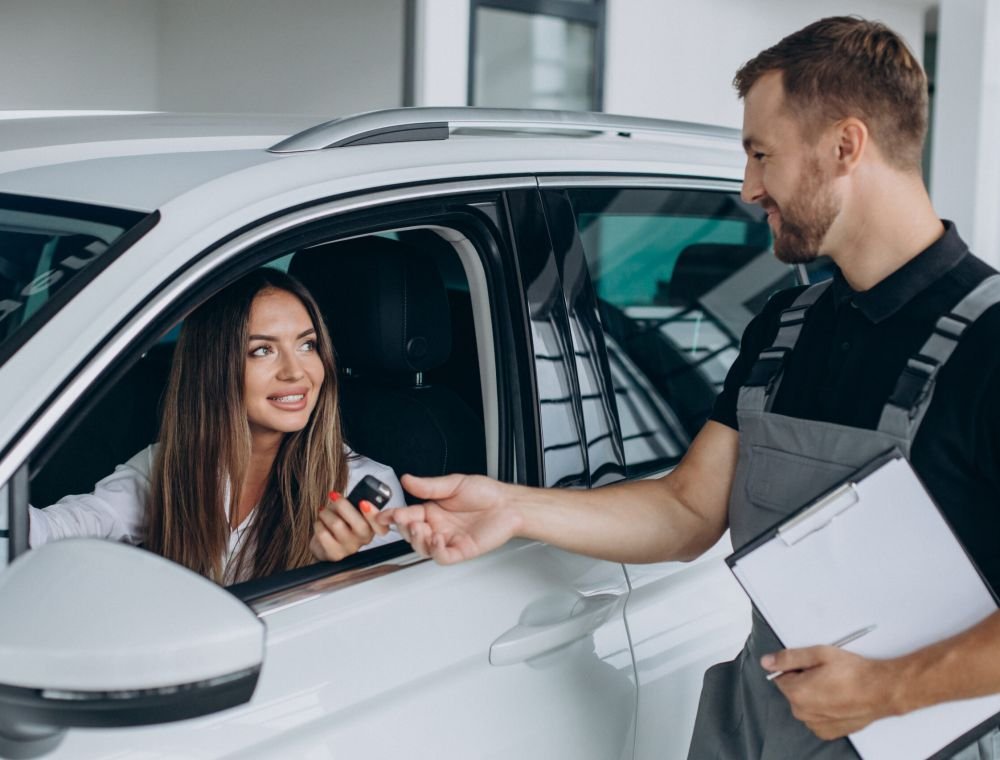 Locksmith handing a replacement key to a customer in their car