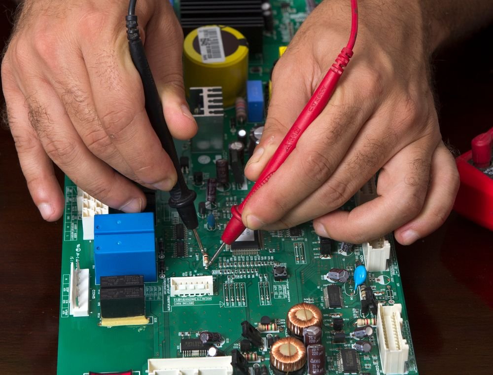 Technician reading a vehicle control module on the bench with test probes